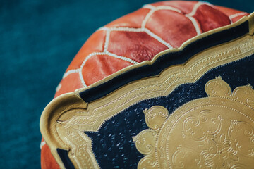 gold and black Florentine tray on brown leather Moroccan pouf, hassock