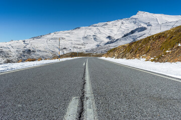 Empty road towards the snow-covered Sierra Nevada mountains. Granada, Spain