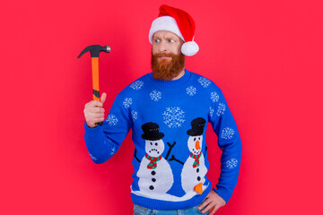 puzzled christmas worker man with hammer isolated on red background. christmas worker man