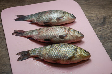 Three raw crucian fish on a cutting board