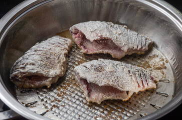 The cook fries crucian fish in a frying pan