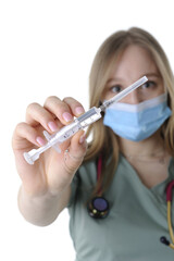 Close-up of the young female physician with a medical face mask and stethoscope holding a syringe against a white background - 546998154