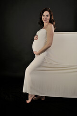 Beautiful pregnant woman in the dress posing isolated on the black - 546998300