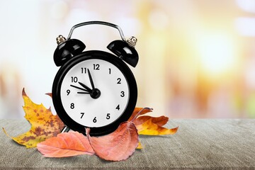Retro alarm clock and autumn leaves background