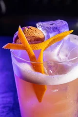 Fotobehang Vertical closeup shot of a cocktail with orange peel and amaretto biscuit © Spolsino Gianluca/Wirestock Creators