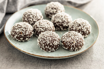 Coconut chocolate balls on plate on kitchen table.