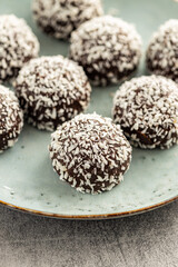 Coconut chocolate balls on plate on kitchen table.