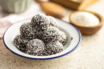 Coconut chocolate balls on plate on kitchen table.