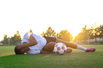 sport, football training, sports injury and people - injured soccer latin player with ball on field