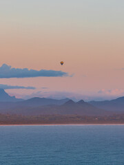 Hot air balloon above the mountains and the ocean.