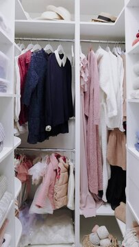 a walk-in wardrobe closet with apparels on hanger rails and shelves