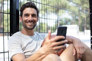 male basketball player taking a rest and using a smartphone
