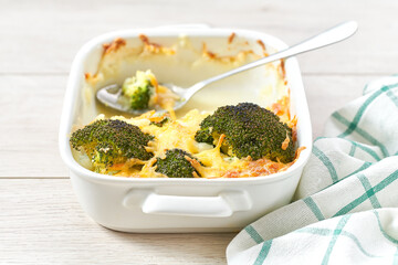 Baked broccoli with cheese in a white baking sheet, close up.