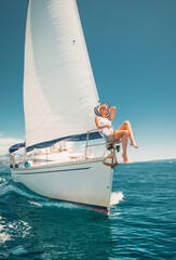 Attractive Woman wearing a hat on a sunny day on the stem of a small sailing-boat
