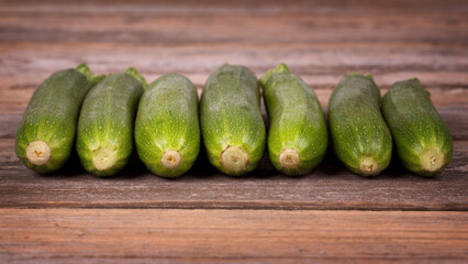 A row of fresh courgettes on an old wooden background. 