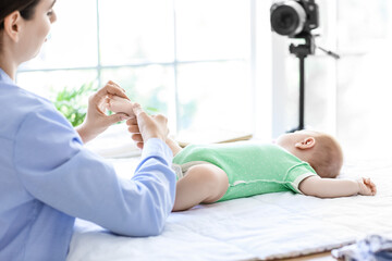 Young woman with little baby recording video course at home