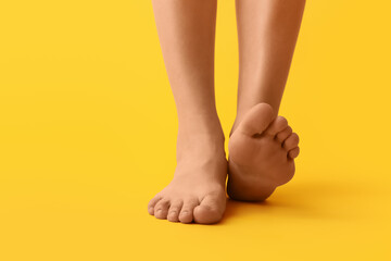 Female barefoot legs on yellow background