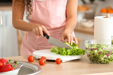 Obraz na płótnie Canvas Young woman making fresh salad in kitchen