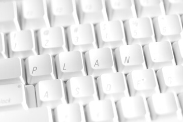 A white keyboard with the letters rearranged to  spell the word Plan