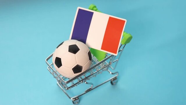 Soccer ball with flag of France in shopping cart on blue background. Football cup earnings.