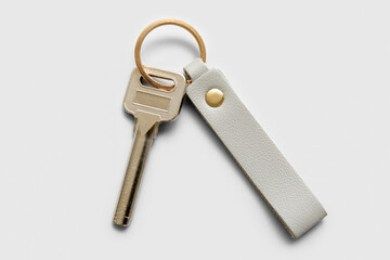 Metal key with leather keychain on white background