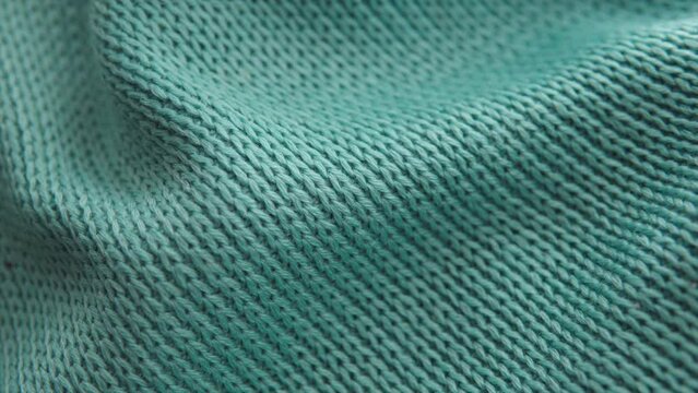 Close-up shot of a soft and cozy green acrylic knitted sweater. 