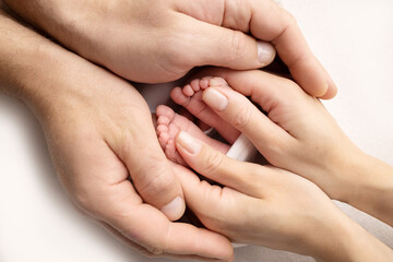 Mother is doing massage on her baby foot. Close up baby feet in mother hands on a white background. Prevention of flat feet, development, muscle tone, dysplasia. Family, love, care, and health concept