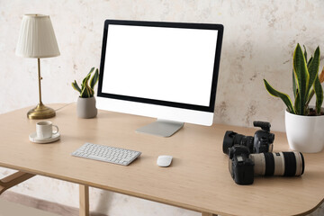 Photographer's workplace with computer and professional cameras near light wall
