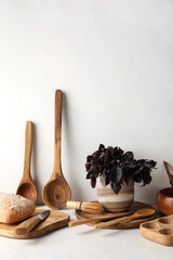 Wooden cooking utensils with bread and basil on white background