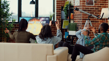 Group of friends losing at video games online competition, playing on tv console at home. People feeling frustrated about lost gaming challenge shooting gameplay, leisure activity.