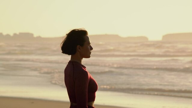 Calm woman standing at the sandy beach and preparing training