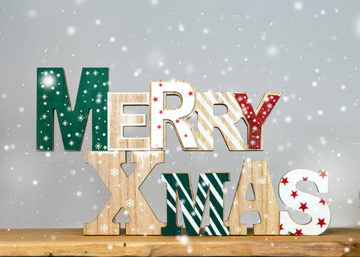 Wooden lettering decoration Merry Xmas sign on a desk with snow falling 