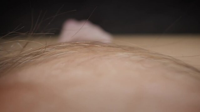 Light skin surface with long dark hair growing on calf of male leg lying on wooden surface at professional studio illumination macro