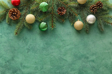 Fir branches with Christmas balls and pine cones on green background