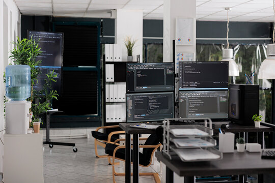 Desk with multiple pc monitors compiling terminal window and artificial intelligence coding database script. Empty software developing agency office with servers cloud programming