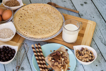 Crepes with chocolate on cutting board with ingredients