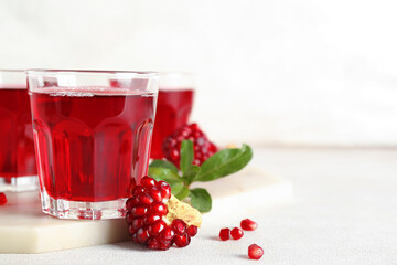 Glasses of fresh pomegranate juice on light background