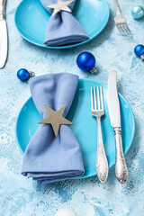 Beautiful table setting with blue plates and Christmas balls on grunge background