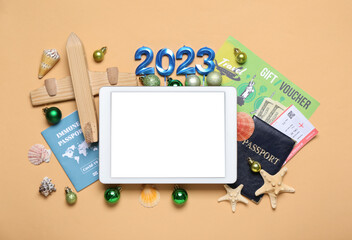 Tablet computer with travel accessories and Christmas balls on beige background