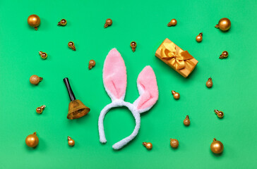 Bunny ears with Christmas bell, balls and gift on green background