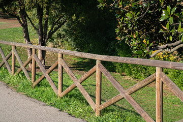 wooden fence, for fencing a park, garden, avenue. Round poles with seasoned wood treated with impregnating agent and paints suitable for outdoor use.