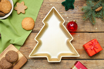 Plate in shape of Christmas tree with cookies, decor and gifts on wooden background