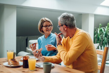 Senior couple eating breakfast at home and spending morning together