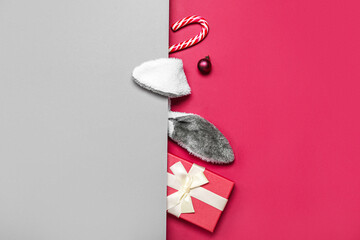 Bunny ears with Christmas ball, gift and candy cane on color background