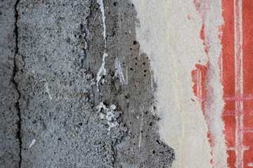 Torn old faded paper wallpaper with a retro pattern. Tattered scraps of paper on a concrete wall. Vintage texture for background and design. Closeup view with copy space. High resolution.