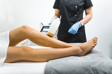 Cosmetology and SPA concept. Bare legs of unrecognizable caucasian young adult woman during laser epilation procedure. Professional equipment. High quality photo