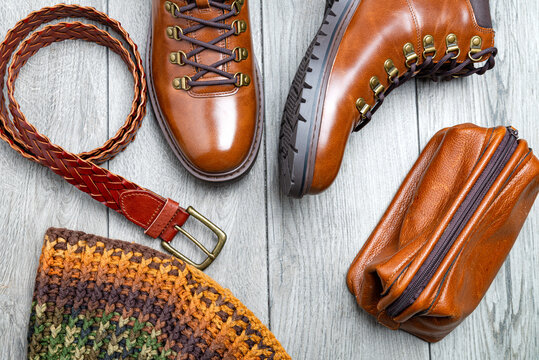 Brown leather men's accessories. Boots, belt and nessesor on a gray, wooden background