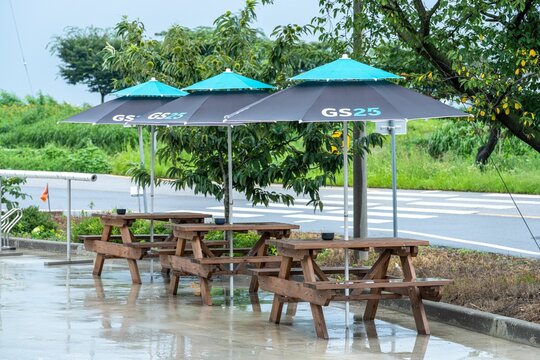 Wooden tables and benches under parasols with GS25 Convenience Store Advertising