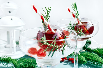 Christmas refreshment drink mimosa, punch or cranberry margarita cocktail serving in christmas ornaments and martini drinking glasses. Delicious icy drink idea for christmas and winter holiday party.