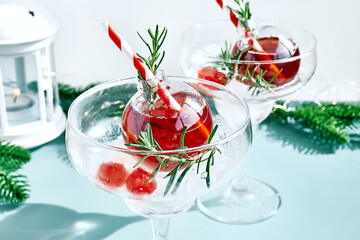 Christmas refreshment drink mimosa, punch or cranberry margarita cocktail serving in christmas ornaments and martini drinking glasses. Delicious icy drink idea for christmas and winter holiday party.